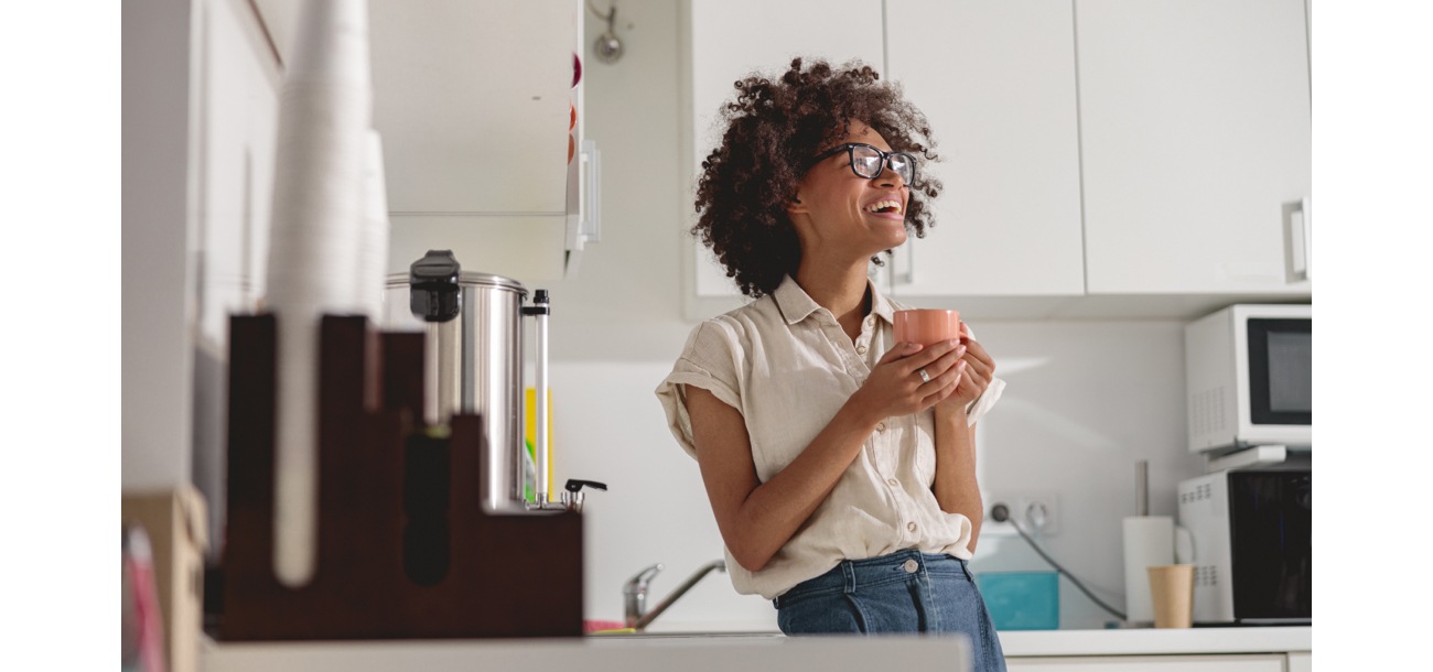 Woman drinking from mug in office kitchen Woman drinking from mug in office kitchen