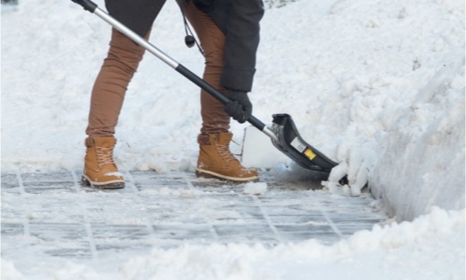 Individual Shoveling Snow on Storefront Sidewalk