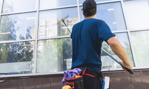 Man on cleaning team washing exterior office building windows.