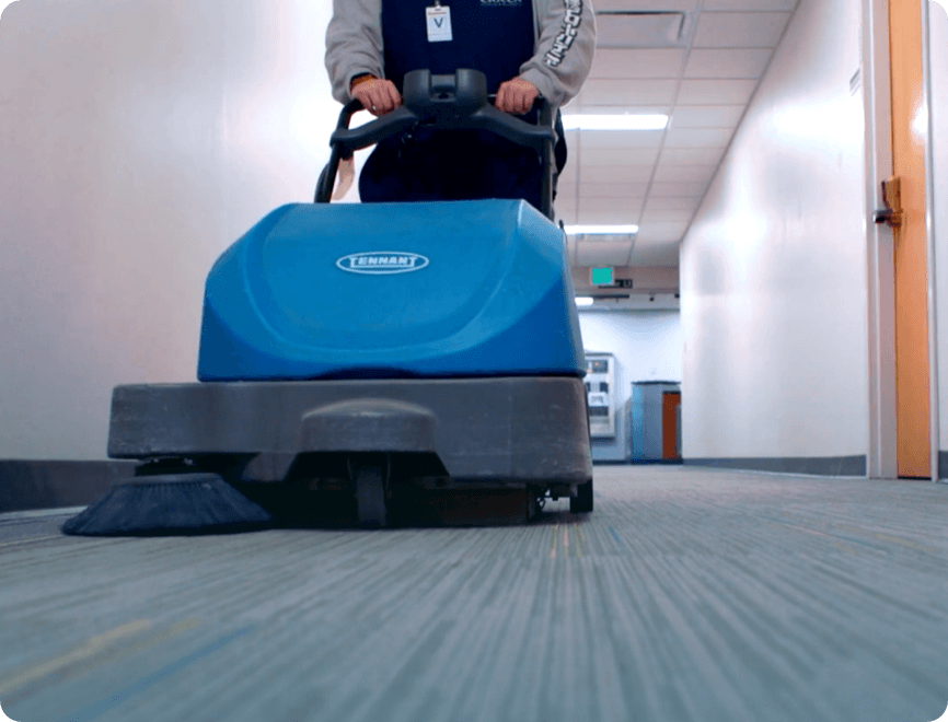Ciocca employee pushing industrial vacuum down business office hallway.