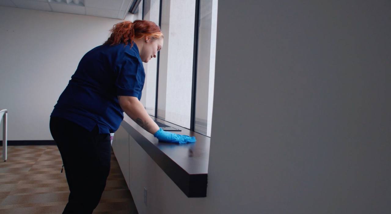Ciocca employee cleaning window in office and area around window