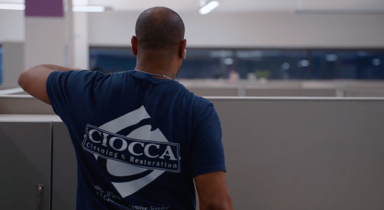 Ciocca employee wearing shirt with Ciocca logo while dusting office cubicle